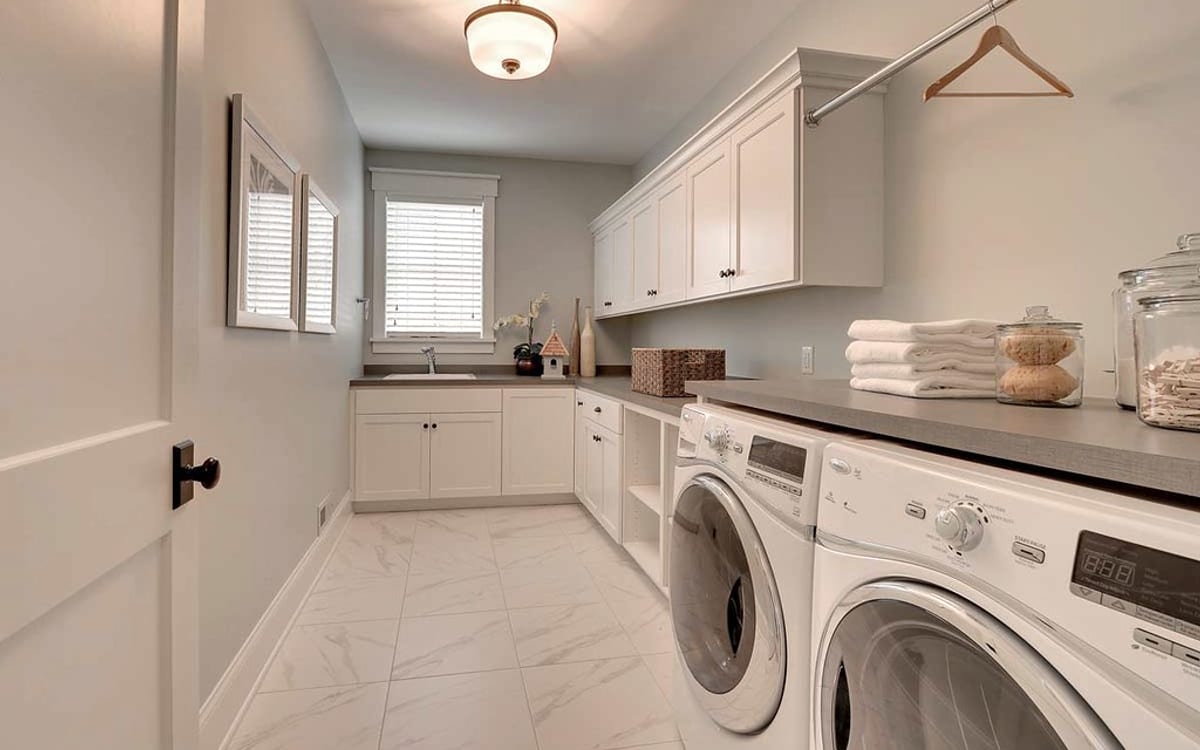 Laundry cabinetry with washing machines, storage cupboards and work surfaces
